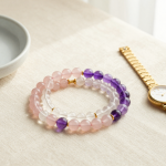Rose quartz, clear quartz and amethyst crystal bead bracelets in a flat-lay beside a slim gold watch