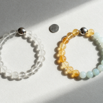 Clear quartz, citrine and blue lace agate bead bracelets mirrored on pale grey plaster with two silver discs and soft morning light