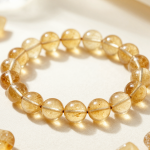 Citrine bead bracelet with warm honey-gold translucent beads, flat-lay on ivory linen with raw citrine points