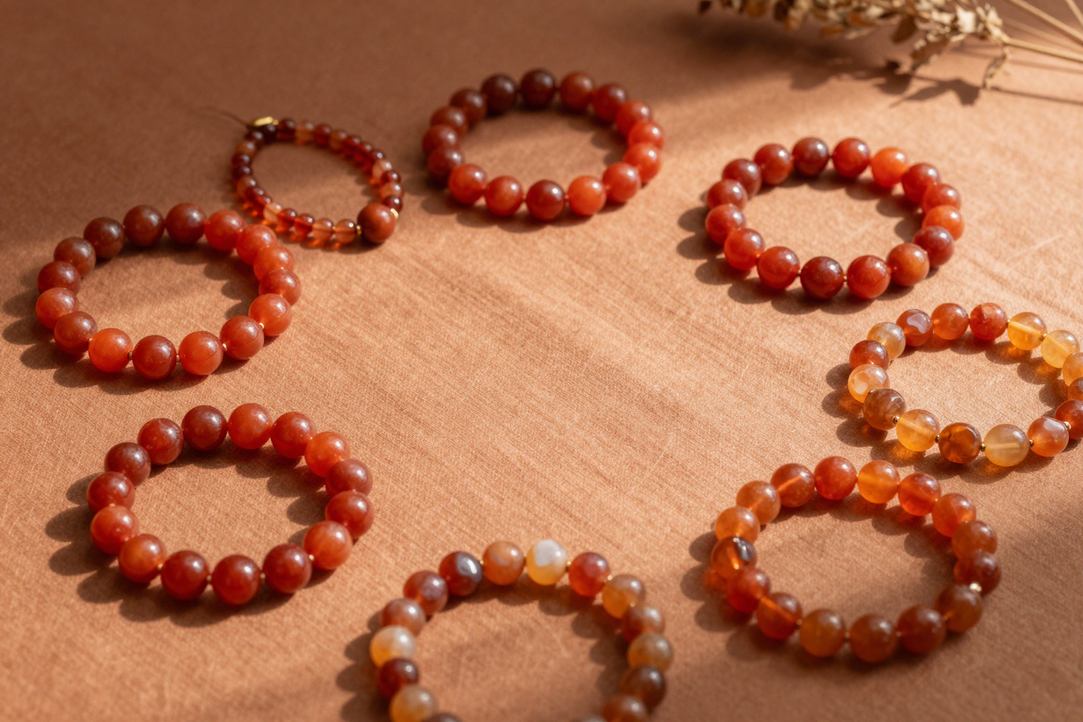Fire element crystal bracelets in red agate, carnelian and citrine arranged on terracotta linen