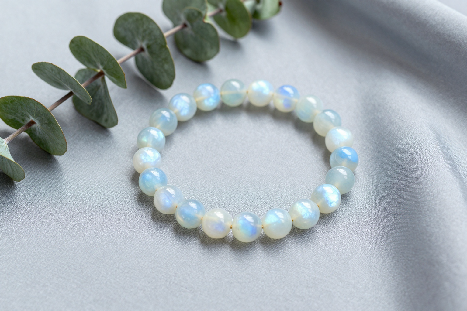Rainbow moonstone bead bracelet with blue adularescence glow on gray silk