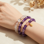 Woman's wrist wearing stacked amethyst, clear quartz and rose quartz beaded bracelets