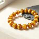 Golden tiger's eye bead bracelet with a silky chatoyant band, flat-lay on cream linen