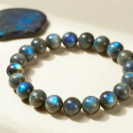 Handmade labradorite crystal bead bracelet with blue labradorescence, flat-lay on ivory linen