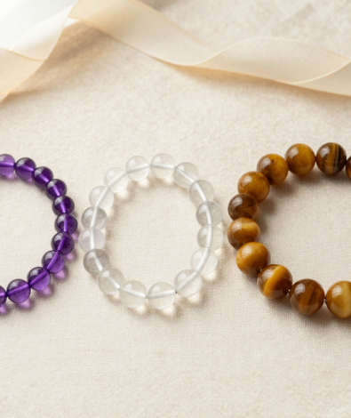Three crystal bead bracelets of different bead sizes on cream linen with a measuring ribbon