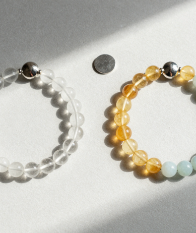Clear quartz, citrine and blue lace agate bead bracelets mirrored on pale grey plaster with two silver discs and soft morning light