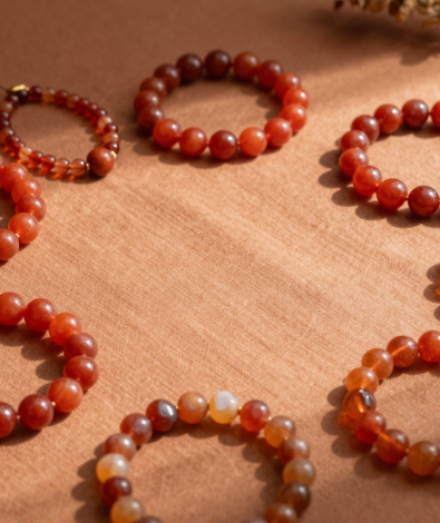 Fire element crystal bracelets in red agate, carnelian and citrine arranged on terracotta linen