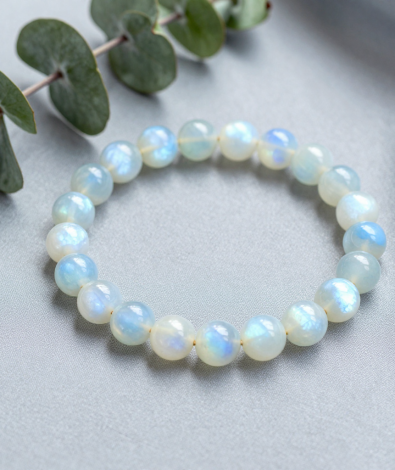 Rainbow moonstone bead bracelet with blue adularescence glow on gray silk