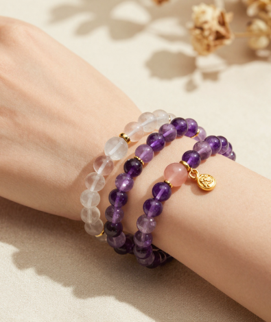 Woman's wrist wearing stacked amethyst, clear quartz and rose quartz beaded bracelets