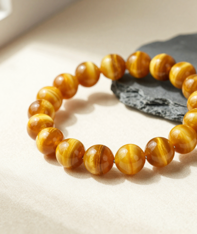 Golden tiger's eye bead bracelet with a silky chatoyant band, flat-lay on cream linen