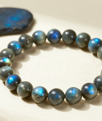 Handmade labradorite crystal bead bracelet with blue labradorescence, flat-lay on ivory linen